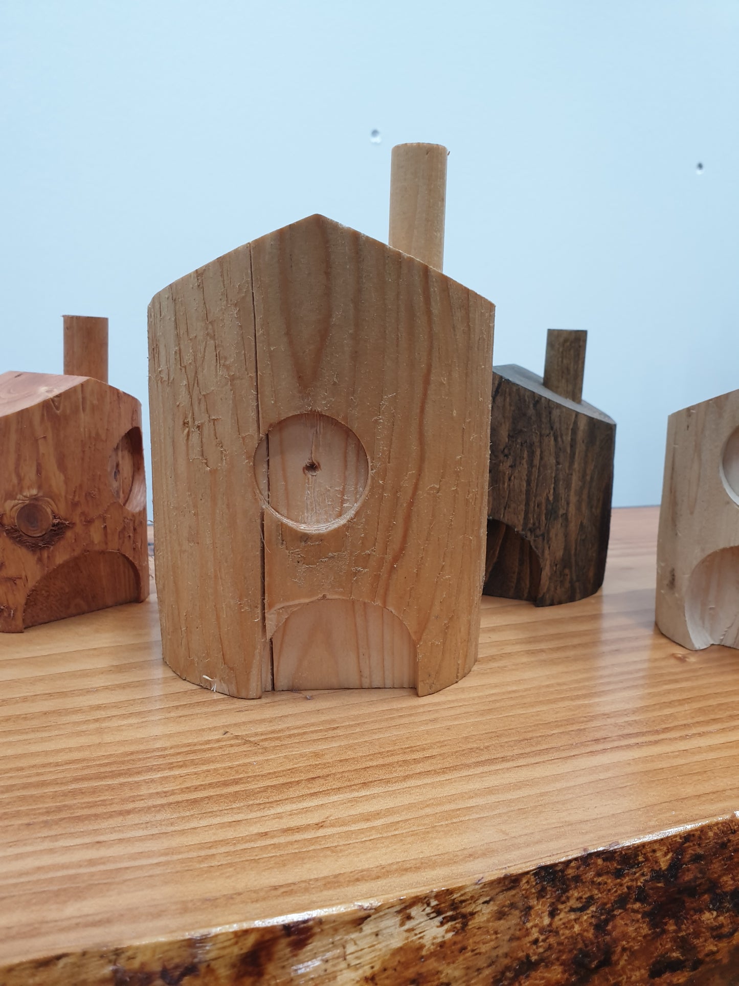 A close up of the 20cm danish oil treated fairy house. It has a central door with a round window directly above the door and a chimney on the right hand side of the roof.