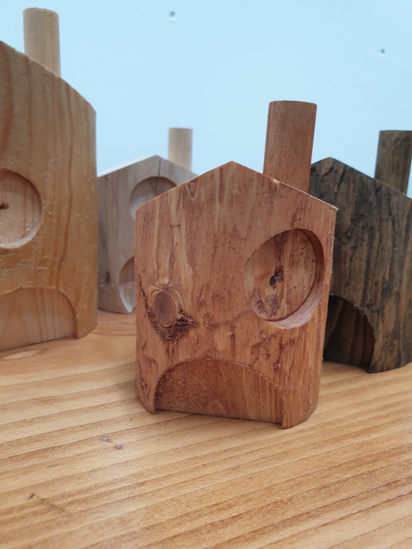 A close up of the 10cm red cedar stained fairy house. it has a central door with an offset window to the right above and a chimney on the right hand side of the roof.