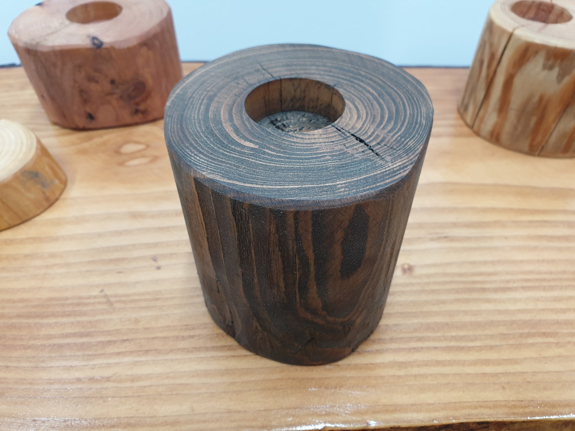 A tall log tea light holder with a dark oak stain