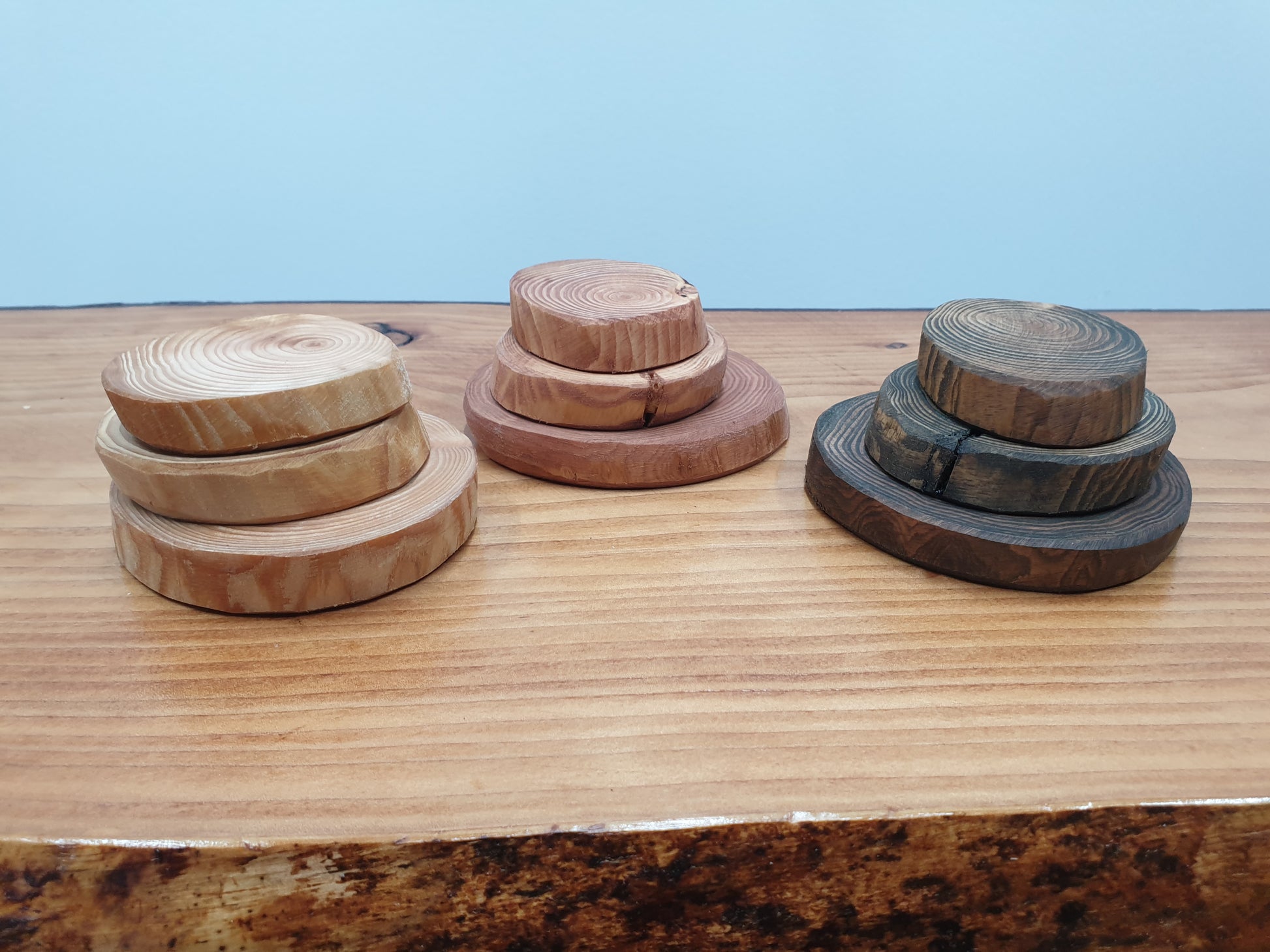 Nine colours and sizes of log ring coasters stacked into three pyramids for display