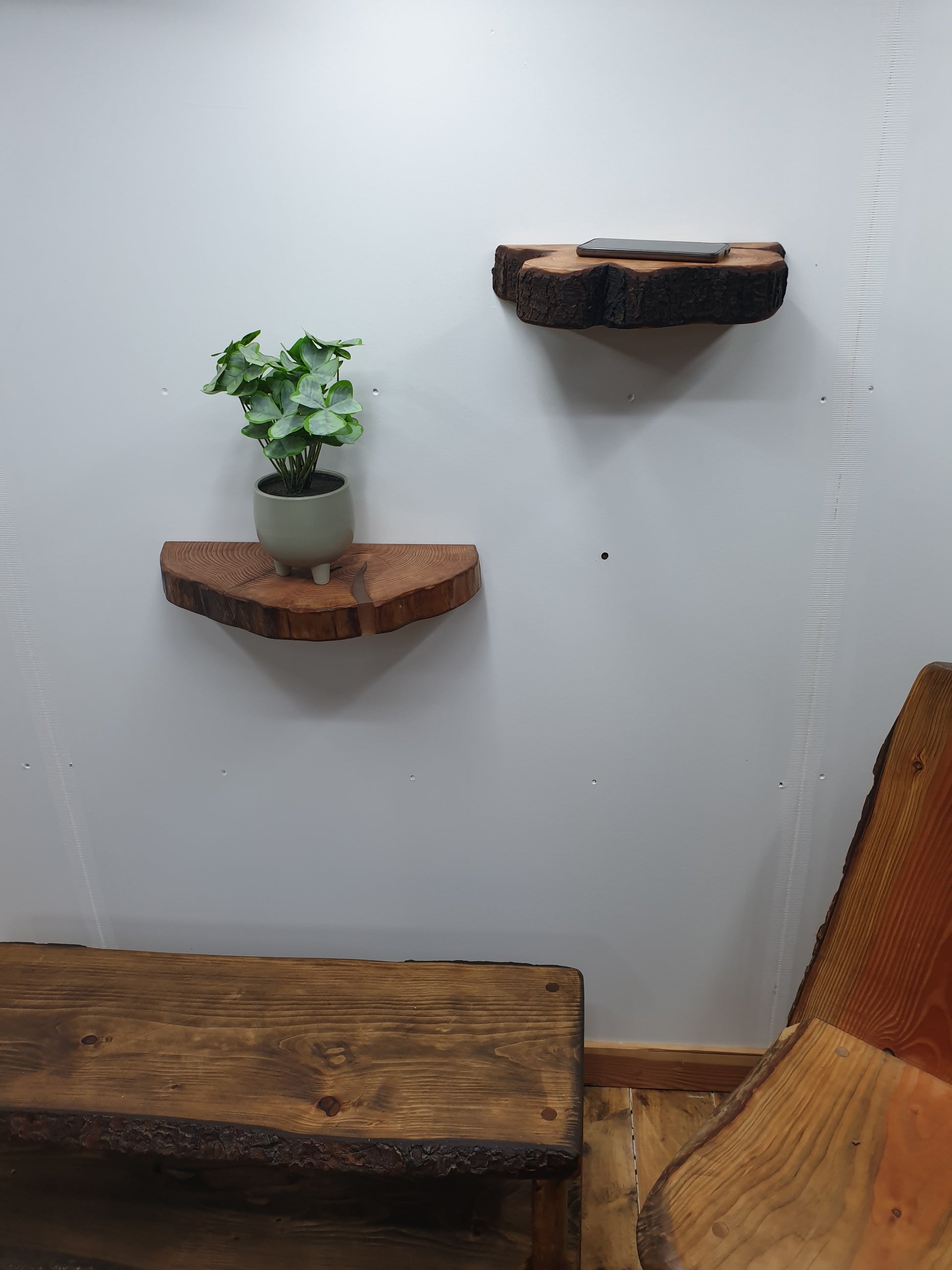 scene of a pair of half log ring floating shelves mounted above a wooden chair and dark oak coffee table