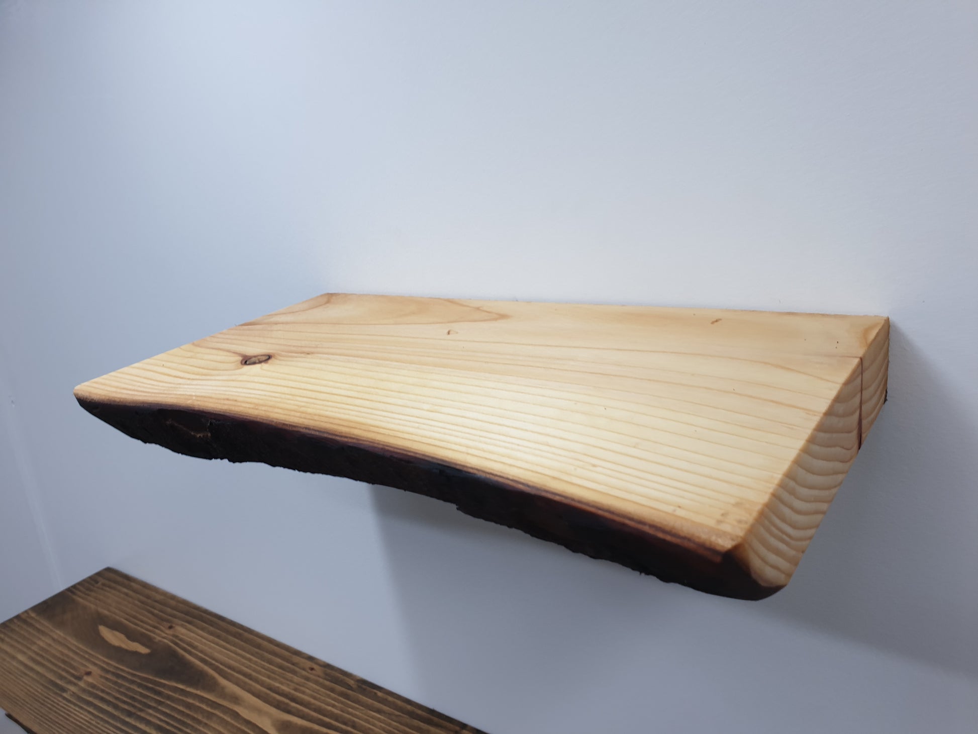 A closeup of a wooden floating wall shelf showing off the live-edge detail.