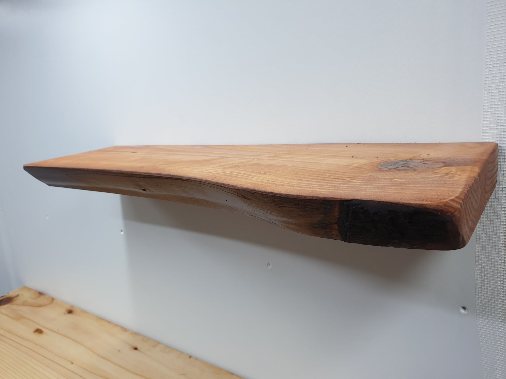 A floating wall shelf treated with a red cedar stain.