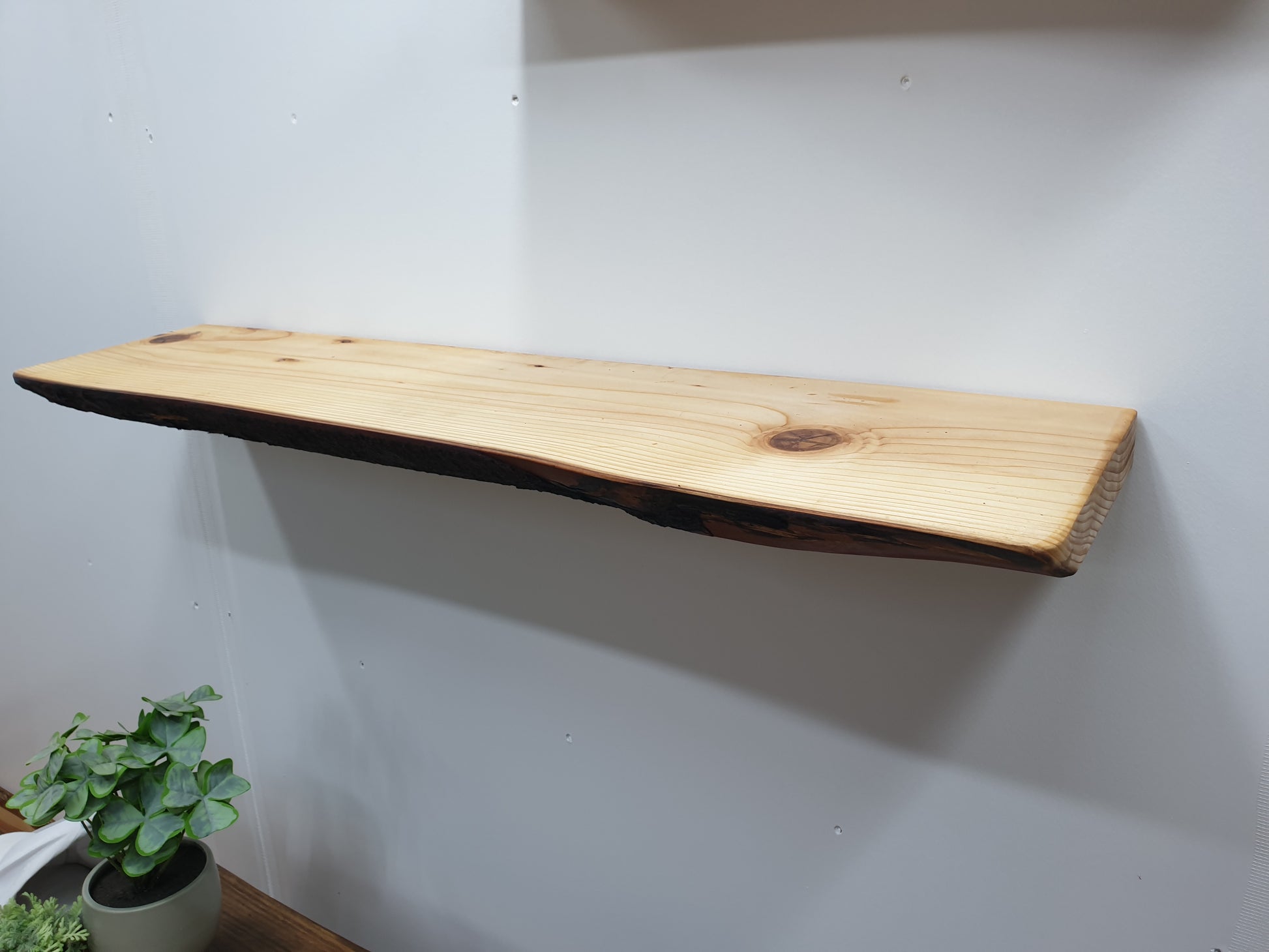 A closeup of a natural wood floating shelf