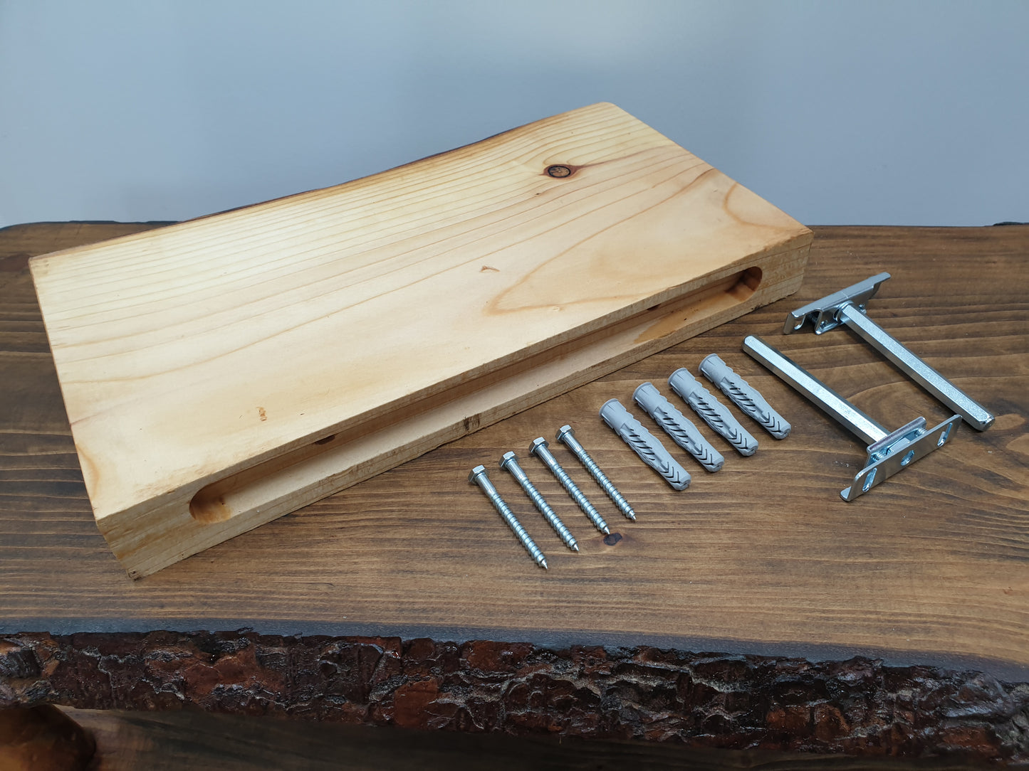 A floating shelf arranged together with its mounting hardware: two brackets, four screws, and four wall plugs.