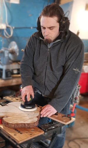 Damien sanding a wooden log ring in his workshop