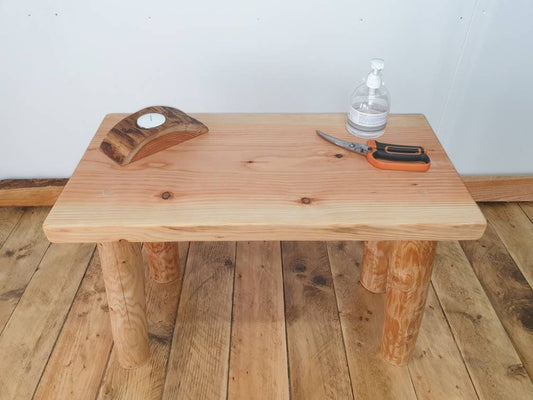 A wooden coffee table, this time without the storage shelf. The table holds a bottle of hand sanitizer, a candle holder, and a pair of scissors. One wonders what the owner of this table is getting up to.