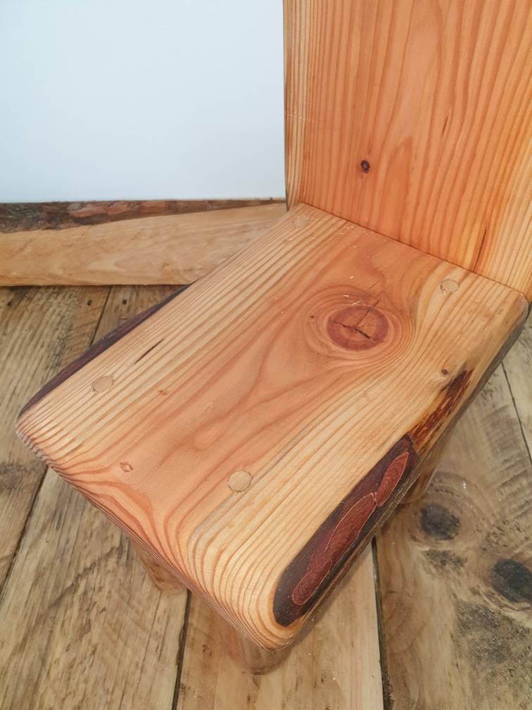 a close up of the seat of a kids throne showing off a large knot detail in the wood of this particular chair