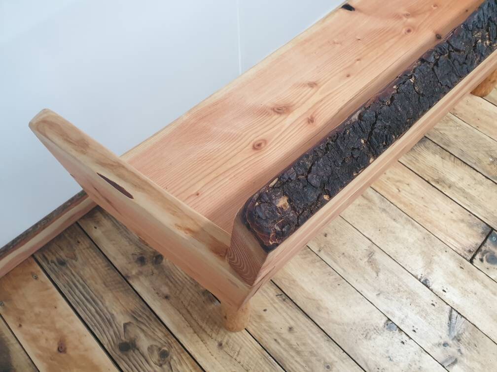 Closeup of the live-edge running along the top of a solid backed garden bench