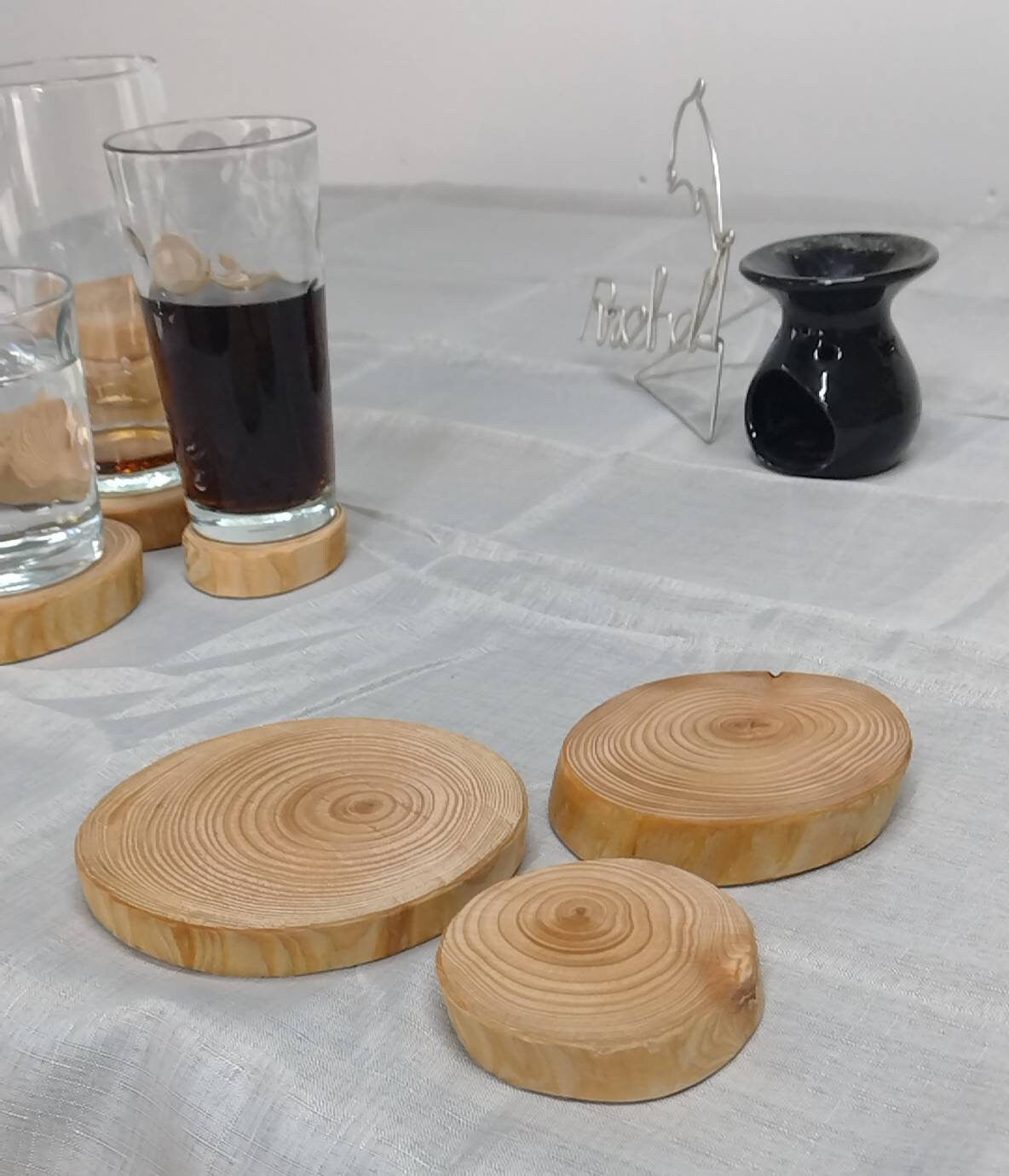 The sizes of natural wood log ring coasters arranged in the foreground with various ornaments in the background