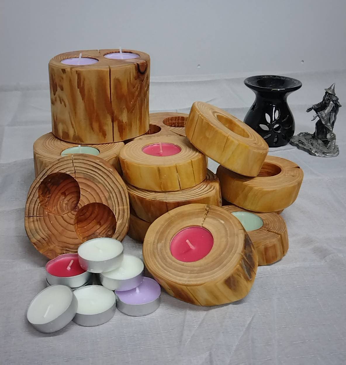 A pile of log tea light holders with various tea lights.