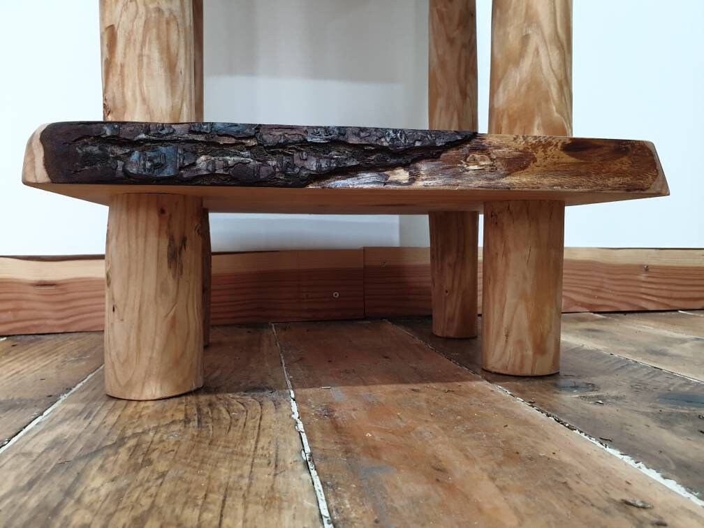 View underneath a wooden end table showing the legs supporting the lower shelf