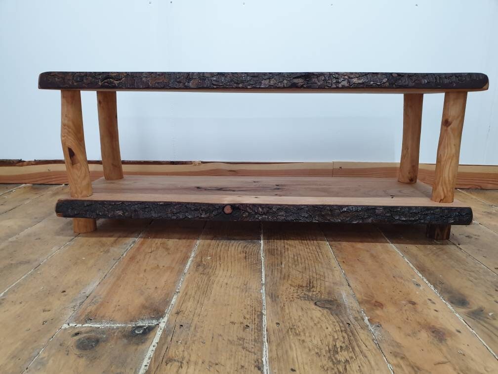 A side view of a wooden life-edge coffee table showing off the storage shelf