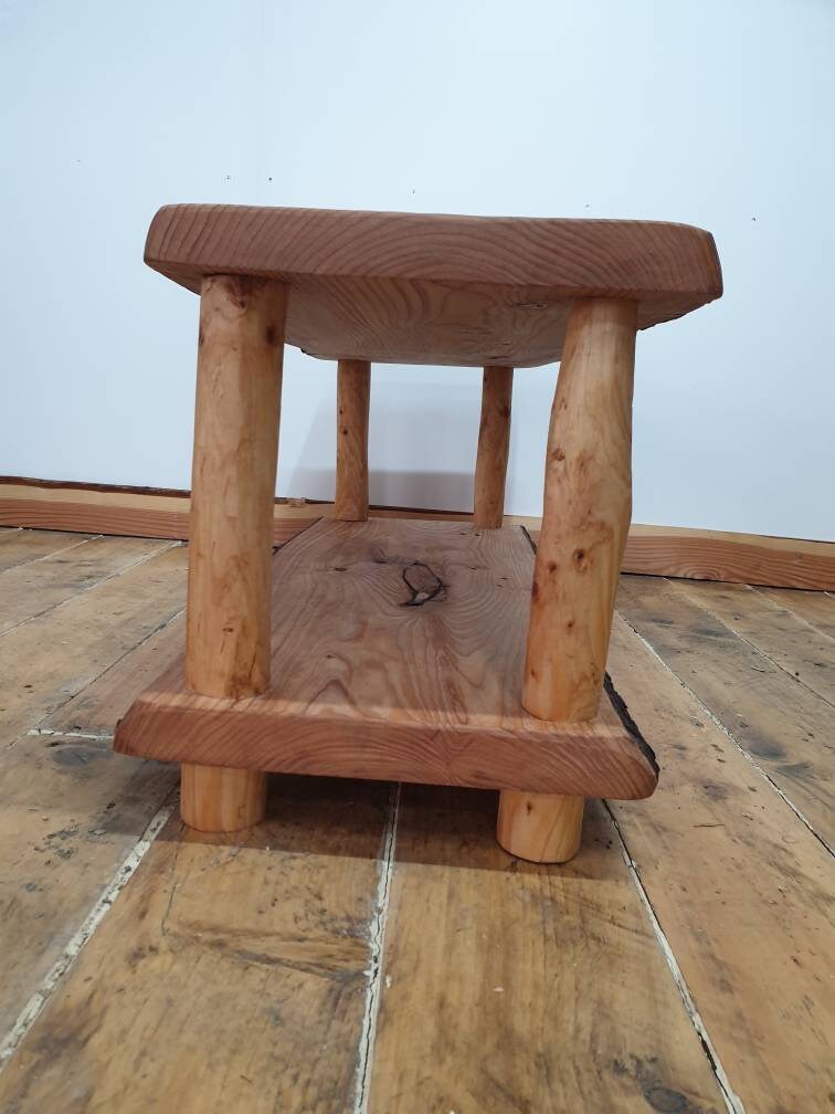 An end view of a wooden coffee table with storage shelf that shows off the end grain of the wood