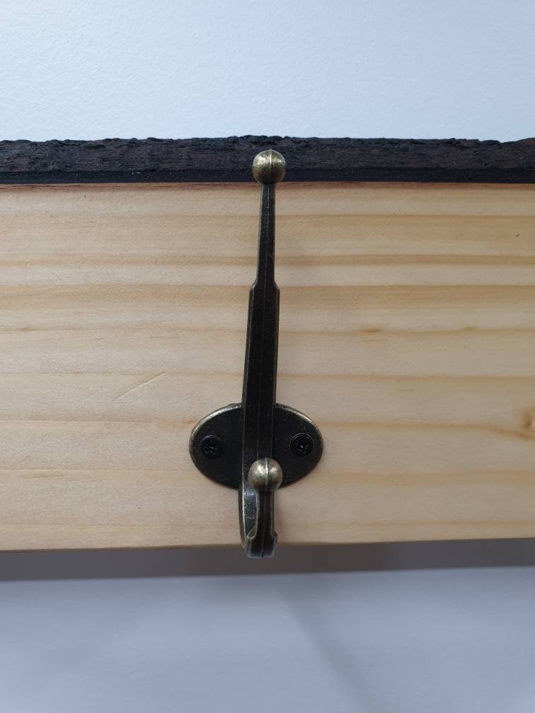 A close up of the hooks used. They are a double hook (one on top of the other) in a tarnished brass finish, secured with 2 small, black, countersunk screws.