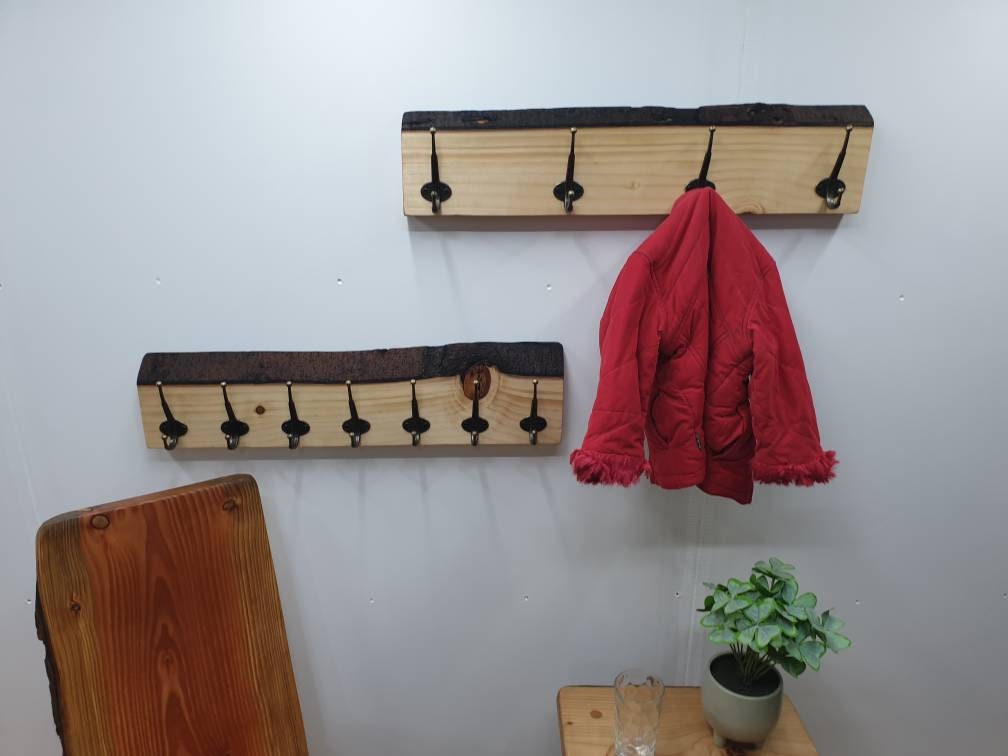 The same 2 70cm coat racks from the front aspect mounted on a white wall. The 4 hook rack has a small red coat hung up on it.