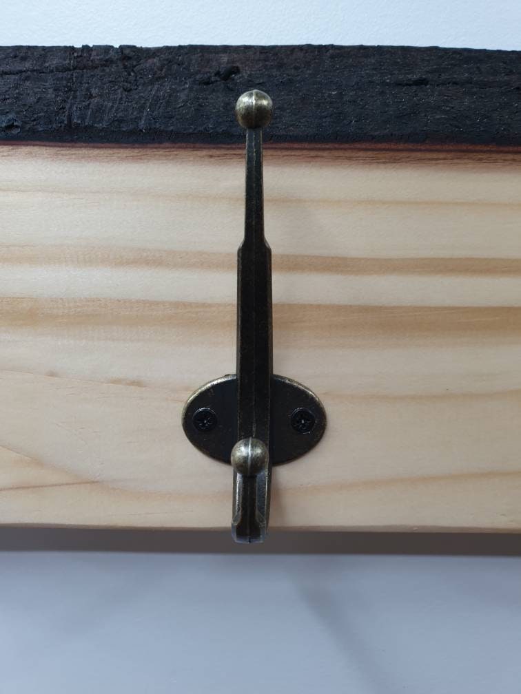 A close up of the hooks used. They are double hooks (one on top of the other) with a tarnished brass finish. They are secured by 2 small, black, countersunk screws.
