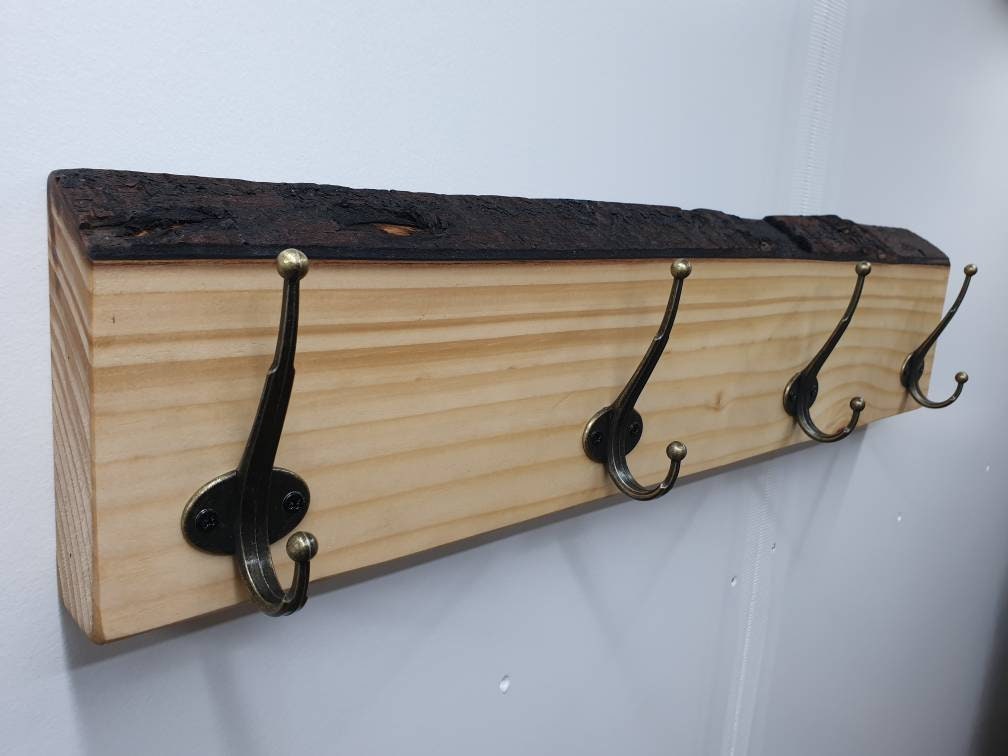 The 4 hook coat rack from the left aspect, mounted on a white wall with nothing hung on it.