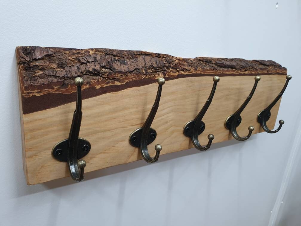 A photo of the previous douglas fir 5 hook coat rack from the left aspect. It has a creamy colour wood grain and a very defined, layered effect of the cross sectioned bark layer.