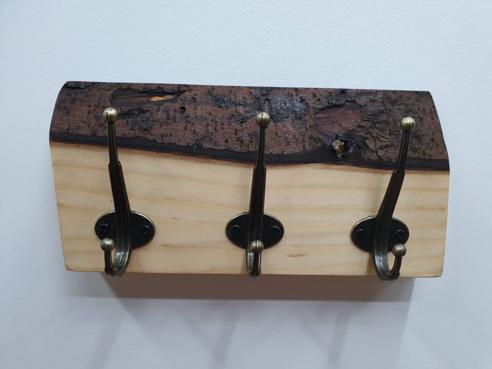 A close up photo of the 3 hook coat rack from the front aspect. Mounted on a white wall and nothing hung on it.