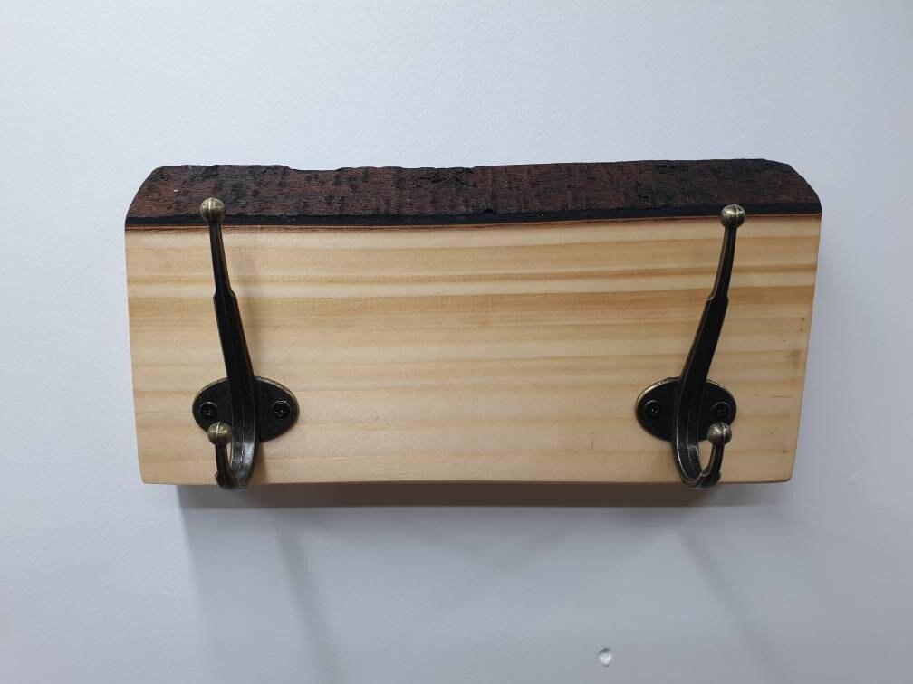 A close up photo from the front of the 2 hook coat rack mounted on a white wall.