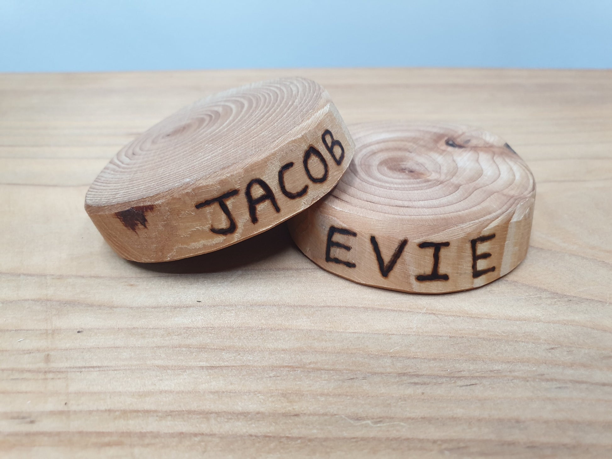 Two log ring coasters with the names "Jacob" and "Evie" burned into the side