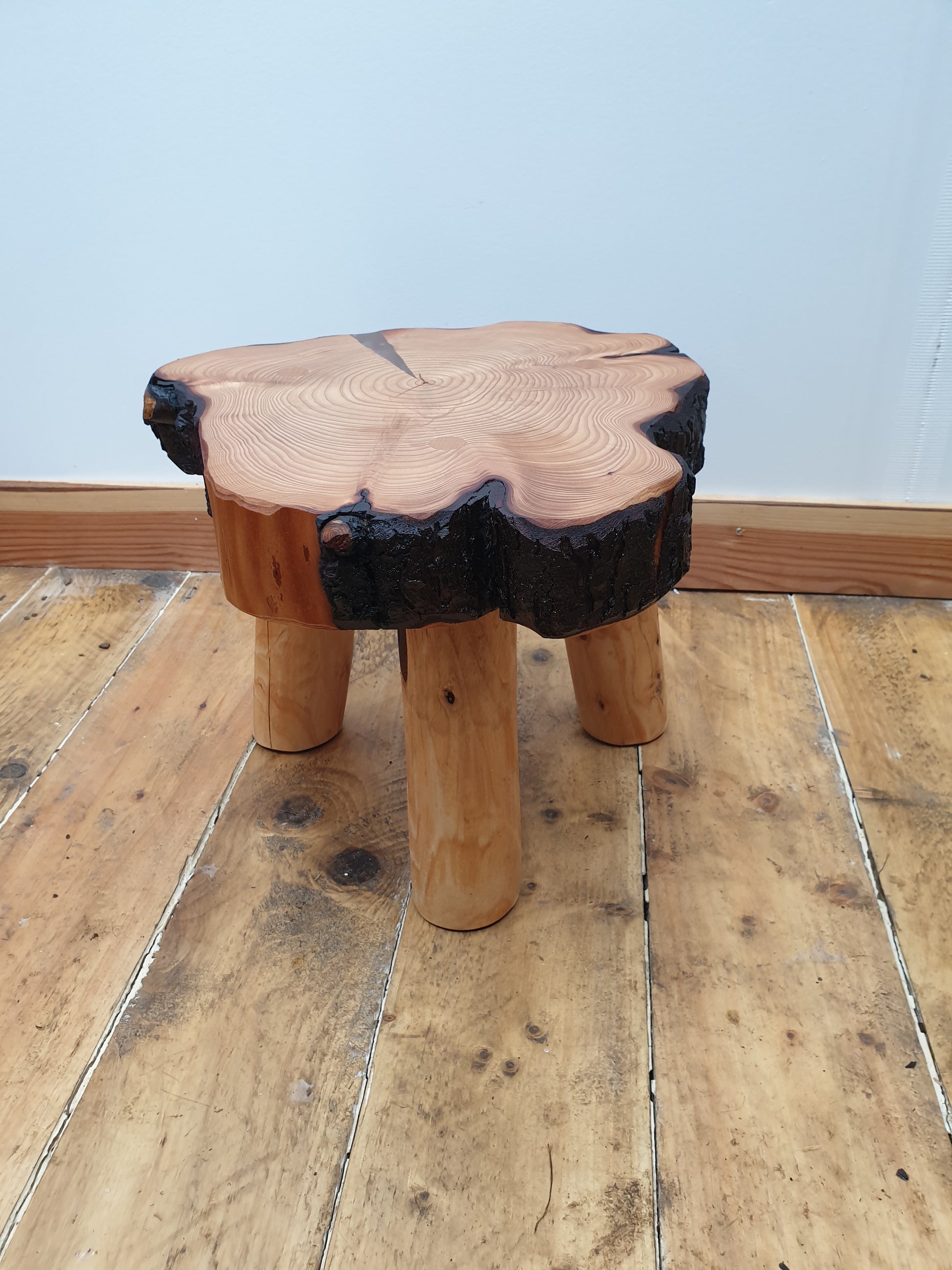 A photo of an irregular shaped 30cm stool. It has a resin filled crack on the top and it has been painted with resin which has given it a lovely shine.