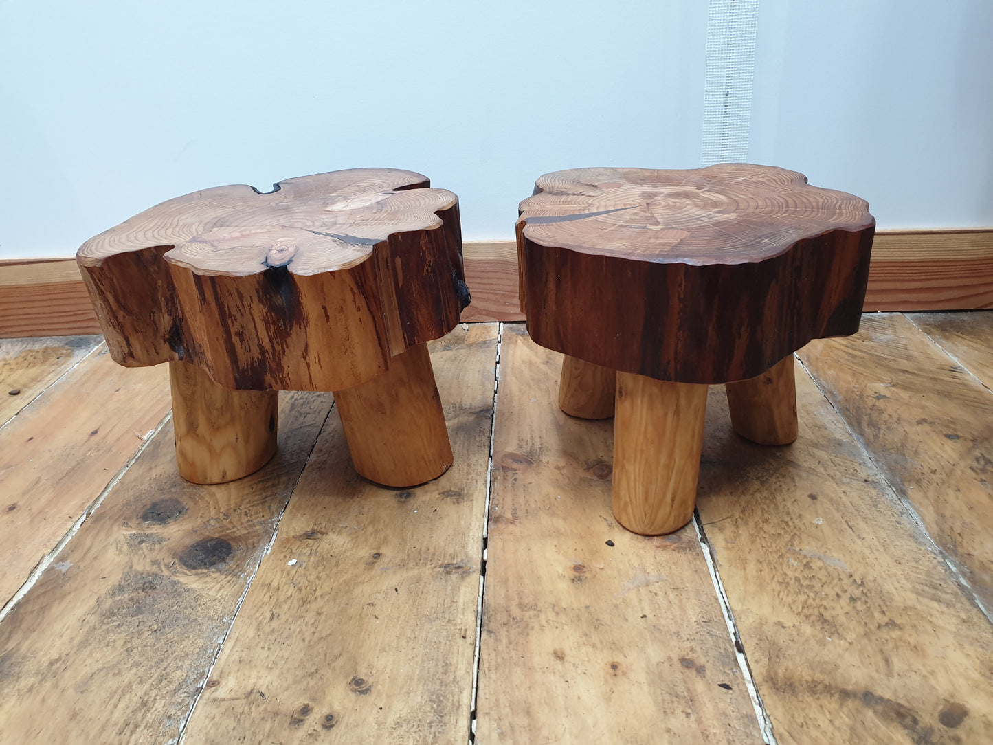 A side view of the same 2 previous stools. sitting at just 20cm they have thick log rings tops and short, round, peeled legs.
