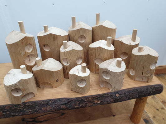 A photo of 12 untreated fairy houses. Many variations in size and details like door and chimney placement and window quantity. 