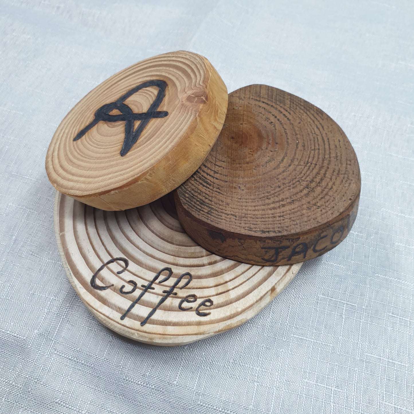 Wooden coffee tampers with 'Coffee' and 'A' branding on a light fabric background