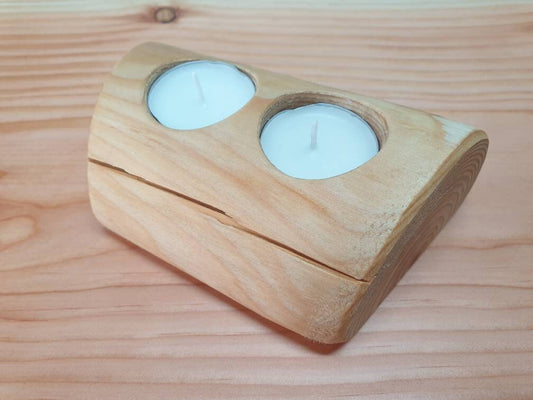 A close up of the 2 holed tealight holder. It is a peeled round log with a flattened bottom so its sits on flat surfaces. It has angled ends to add character and has 2 white tealights in for display.