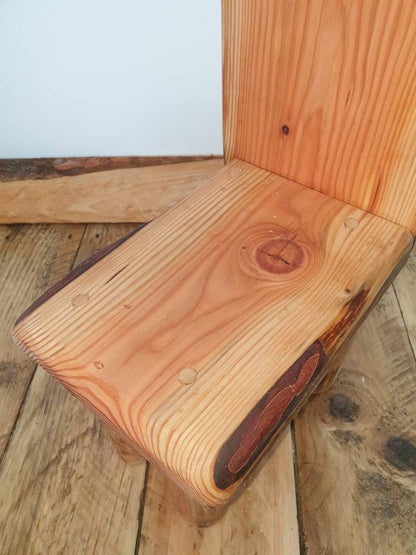 a close up of the seat of a kids throne showing off a large knot detail in the wood of this particular chair