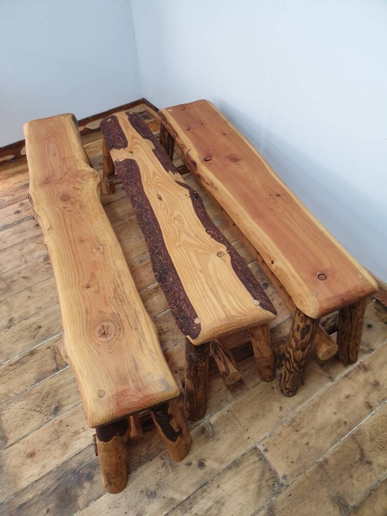Three long wooden benches showing off the variation. The left bench is relatively plain, the middle has a significant amount of bark still attached, and the right bench has a deep red heartwood.