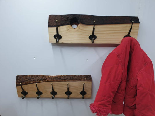 A photo of 2 50cm coat racks mounted on a white wall. 1 has 3 hooks and is made with spruce, this is a white wood grain and a chocolate brown bark colour, it has a natural hole between 2 hooks where a branch once was. The other has 5 hooks and made from douglas fir, it has a slightly redder grain and a more characterful caramel colour bark layer.