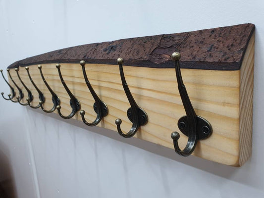A 90cm coat rack from the right aspect, it has a total of 9 hooks and is mounted on a white wall with nothing hung on it.