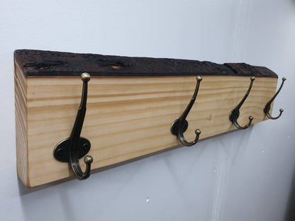 The 4 hook coat rack from the left aspect, mounted on a white wall with nothing hung on it.